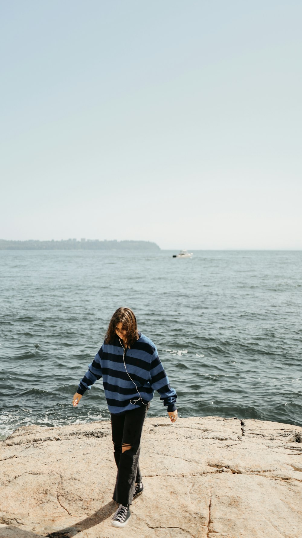 a woman standing on top of a rock next to the ocean