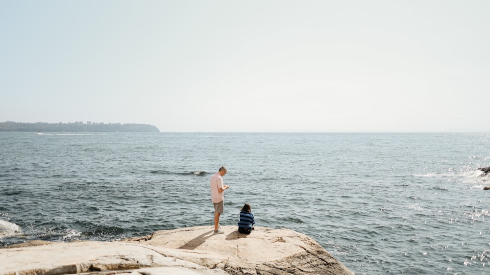 a man standing on a rock next to a child