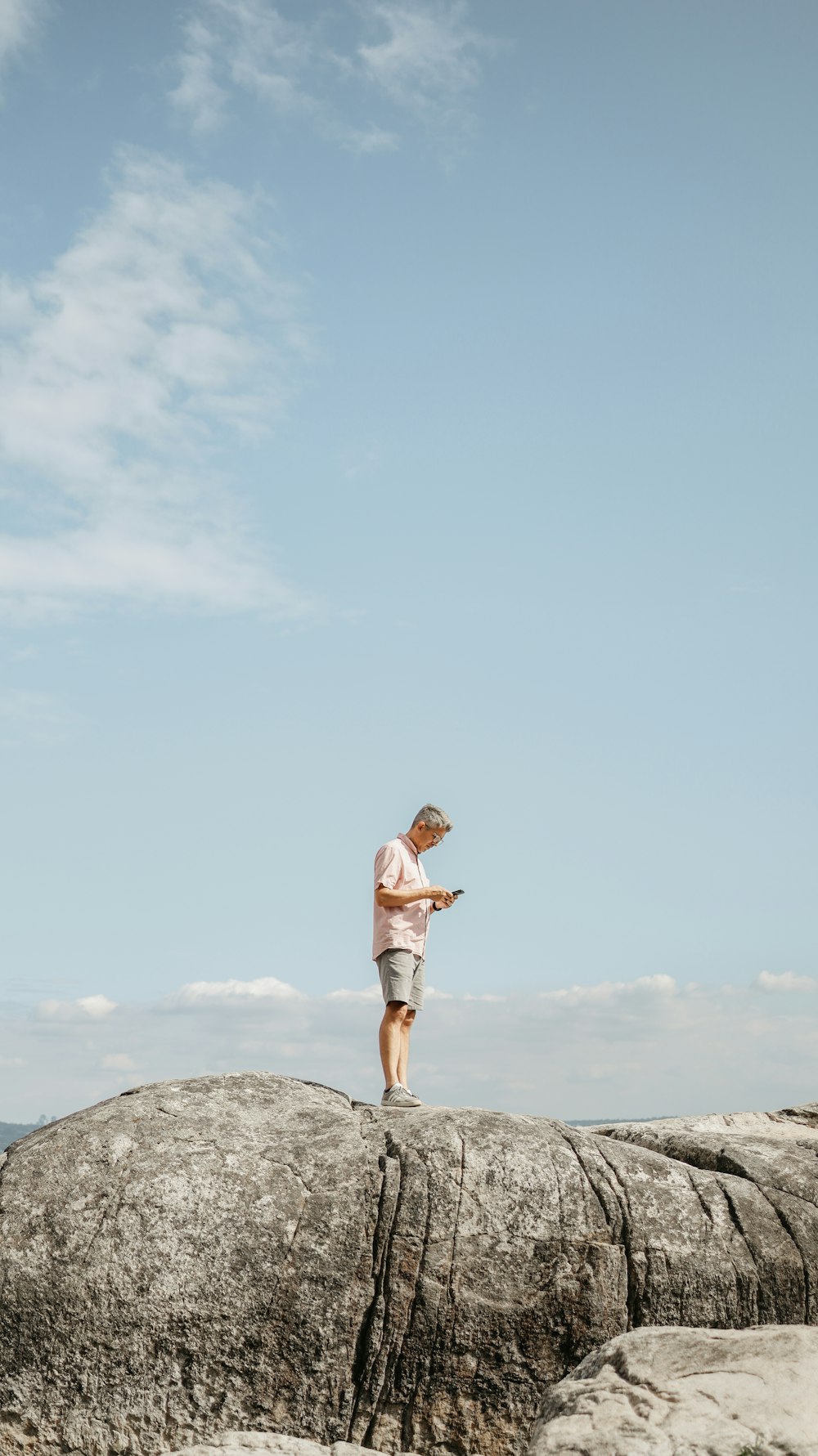 a man standing on top of a large rock next to the ocean