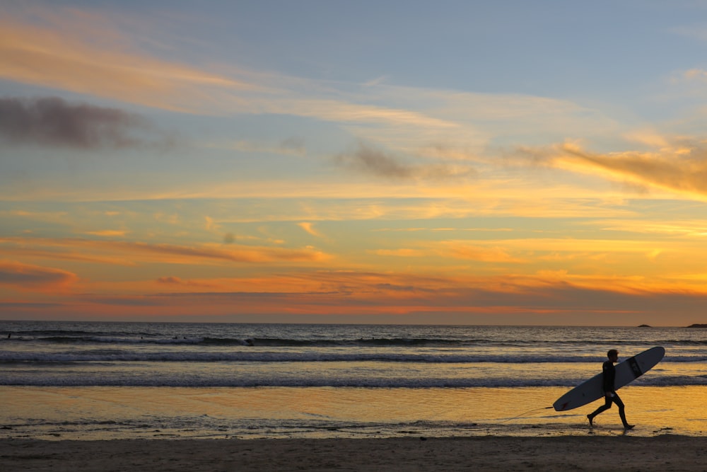 a person walking on the beach with a surfboard