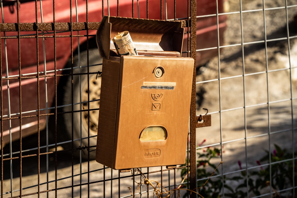 une boîte aux lettres attachée à une clôture avec un camion rouge en arrière-plan