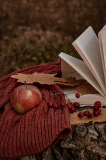 A cozy wool beret resting on a rustic wooden table with autumn leaves scattered around.