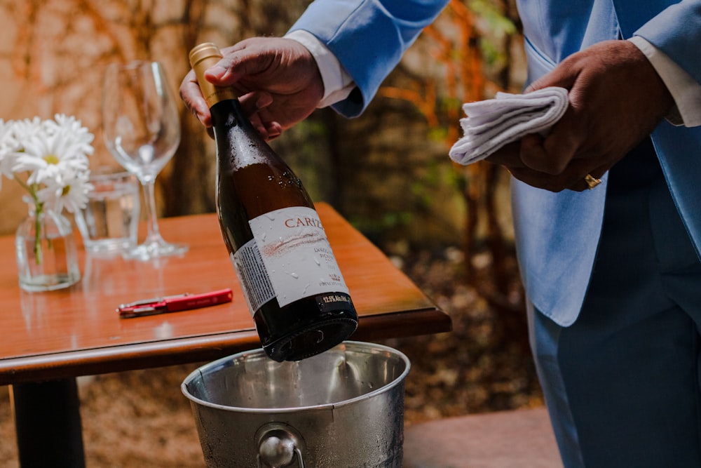 a man pouring a bottle of wine into a bucket