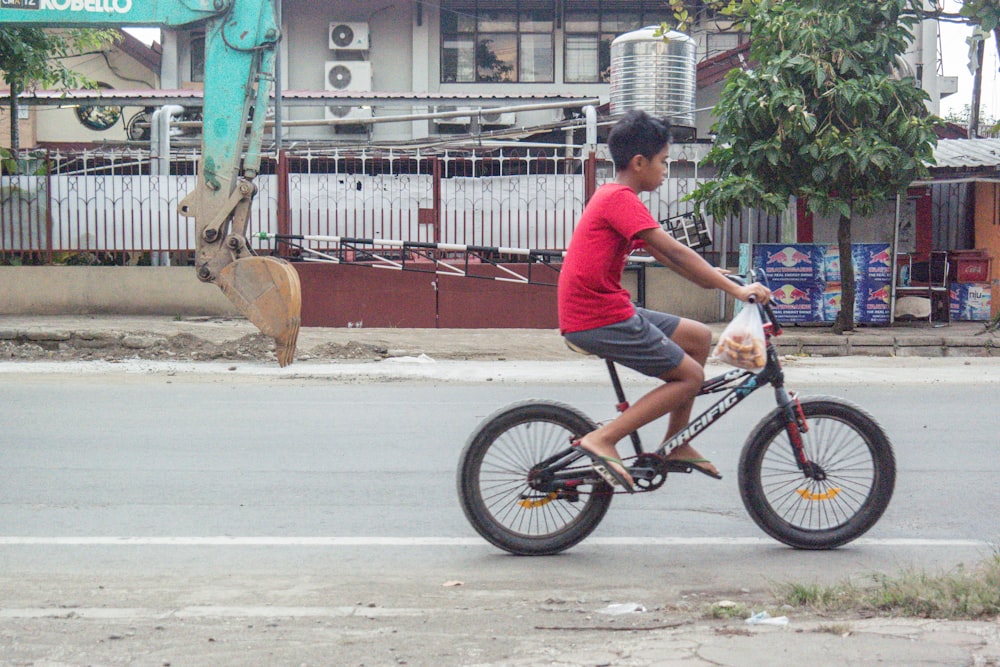 a young boy riding a bike down a street