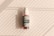 A cosmetic bottle with a pump is positioned against a background with diagonal light and shadow patterns. The bottle features a decorative label with intricate designs and the word 'Cosmetic' prominently displayed.