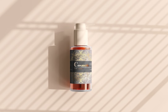 A cosmetic bottle with a pump is positioned against a background with diagonal light and shadow patterns. The bottle features a decorative label with intricate designs and the word 'Cosmetic' prominently displayed.