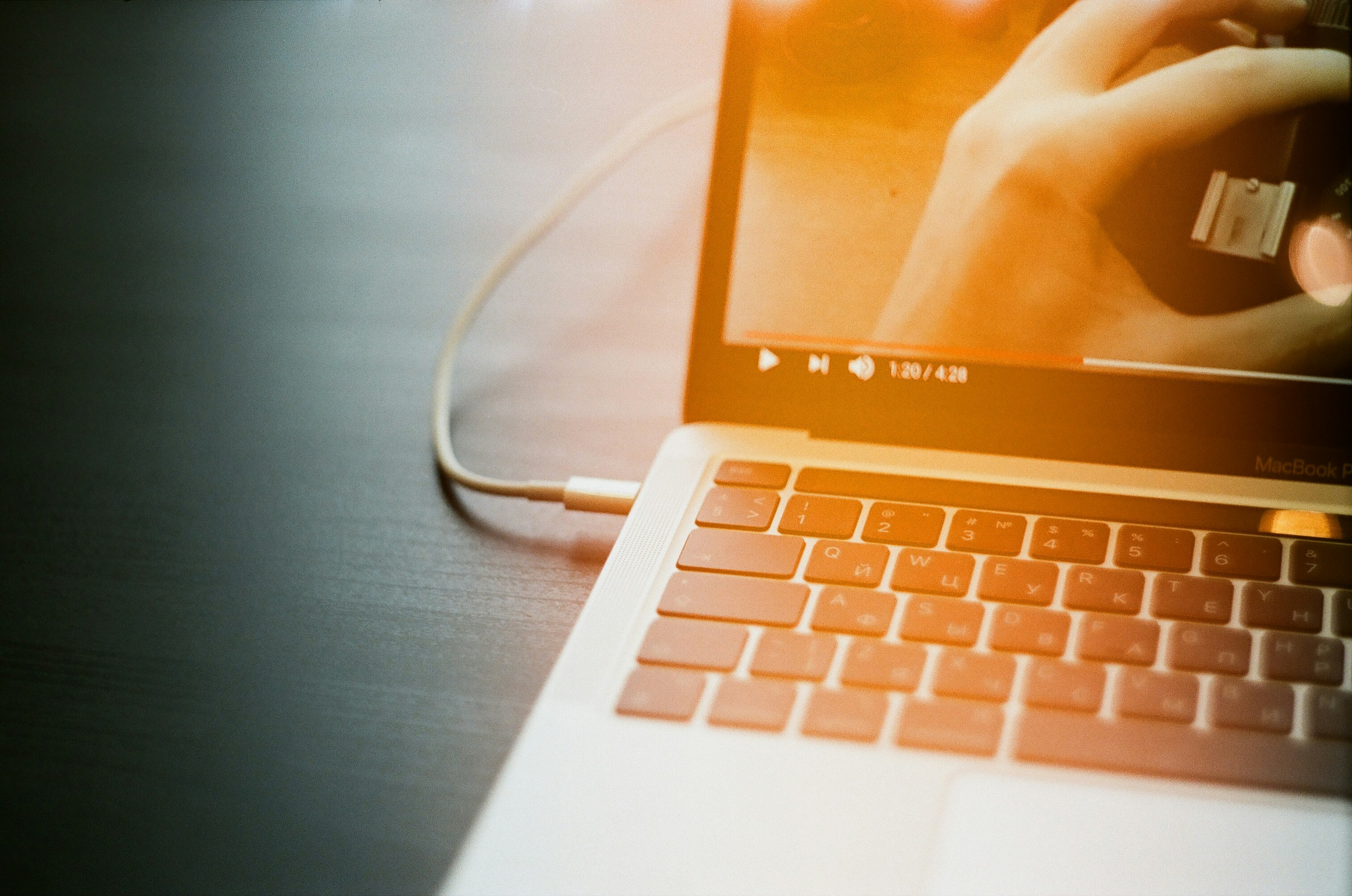 A laptop open and playing a video, with a cord attached. 
