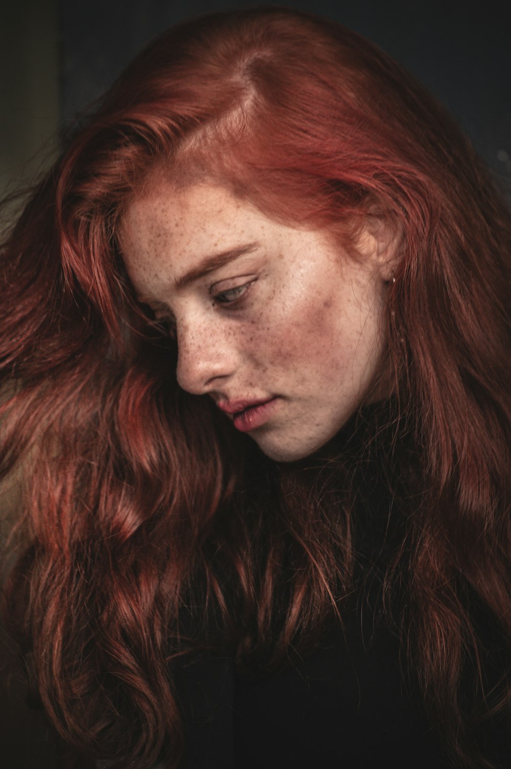 a woman with freckled hair is looking down