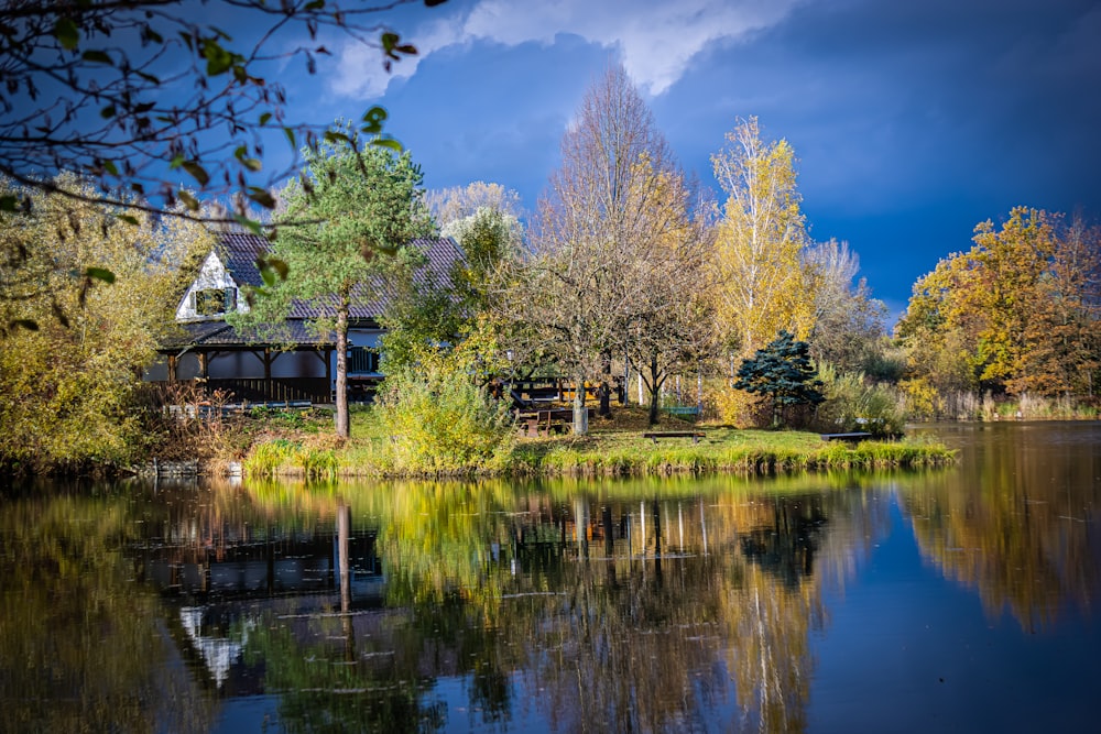 a lake surrounded by trees with a house in the background