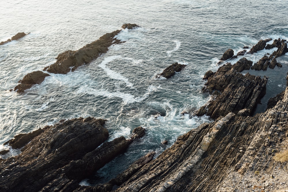 an aerial view of the ocean and rocky coastline