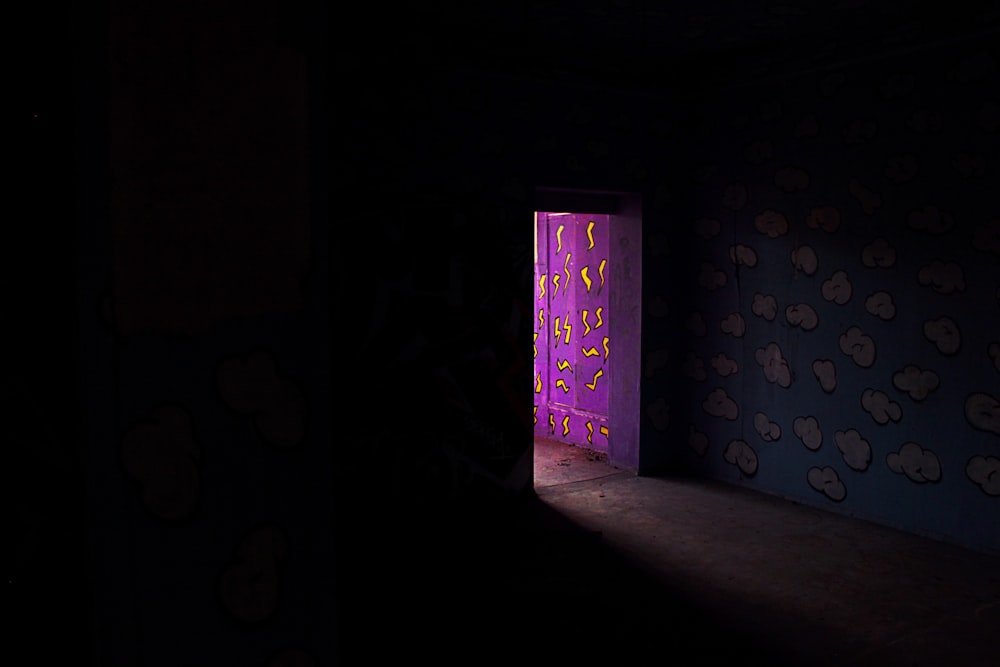 a dark room with a purple light coming through the door