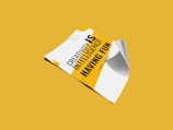 A piece of paper is displayed on a yellow background, featuring a motivational quote in bold black and yellow text. The paper appears slightly curled at the edges.