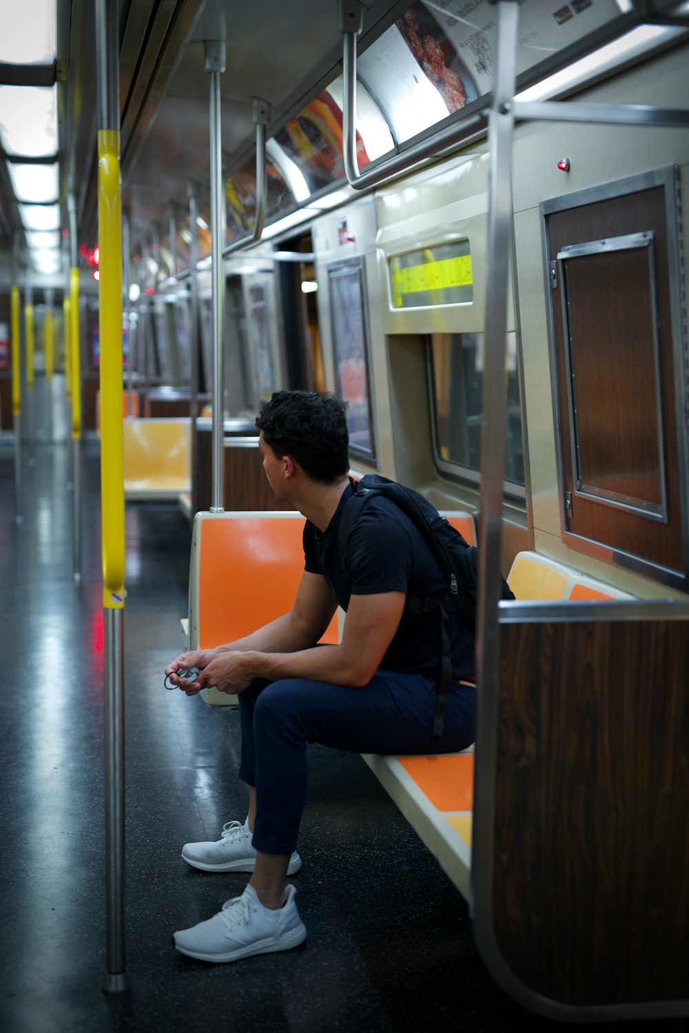 a man sitting on a subway looking at his cell phone