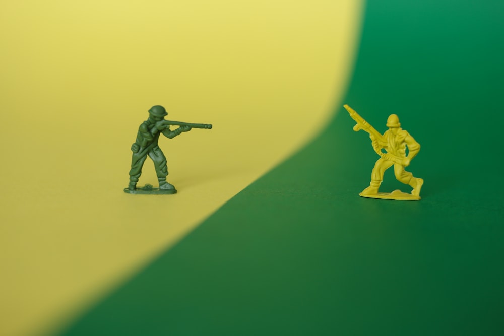 Un soldado de juguete sosteniendo una pistola junto a un soldado de juguete