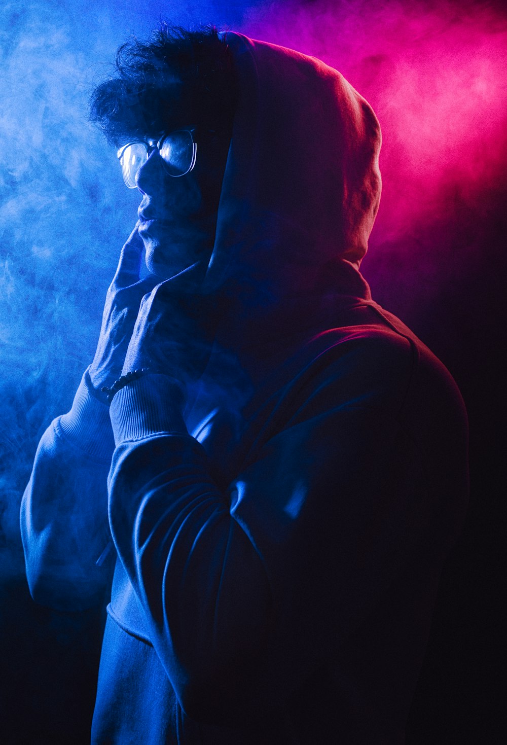 a man in a hoodie standing in front of smoke