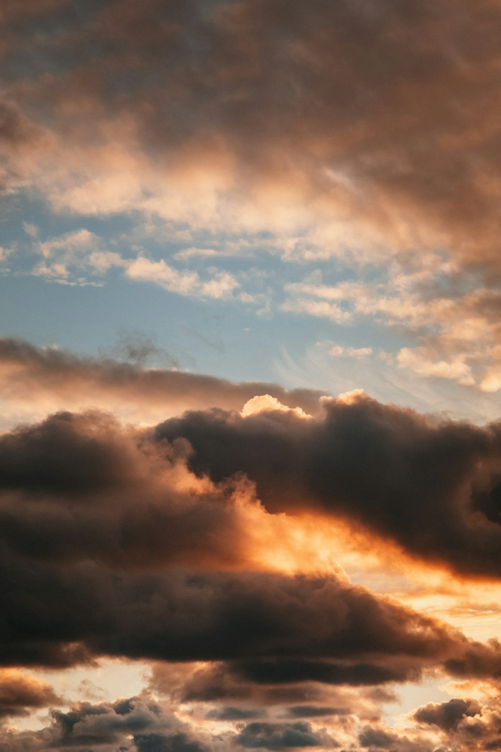 um avião voando através de um céu nublado ao pôr do sol