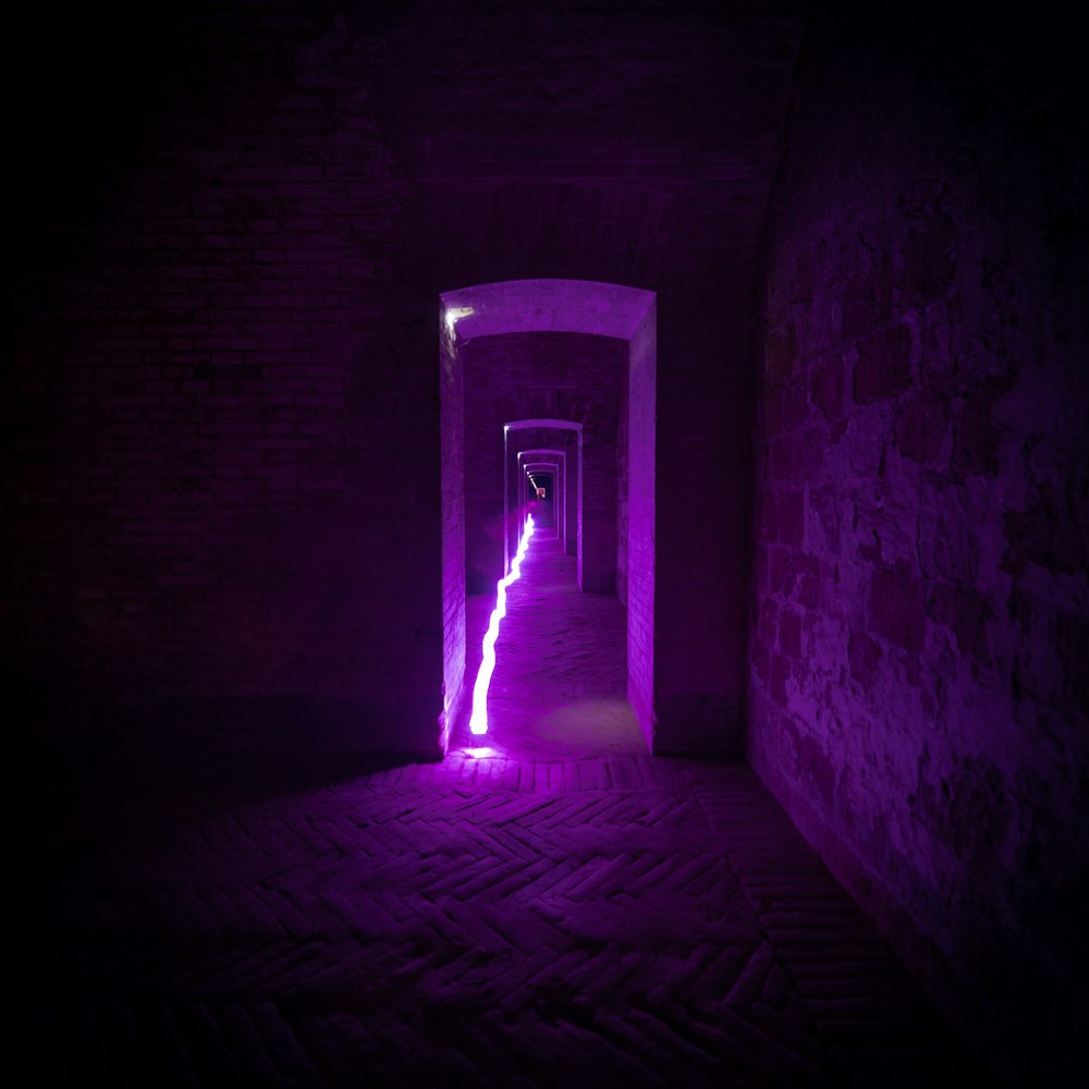 a dark tunnel with a purple light at the end