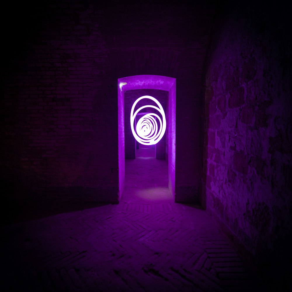 a dark room with a purple light at the end of the tunnel