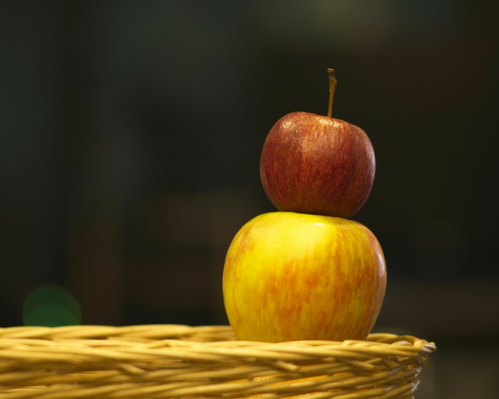 a yellow and red apple sitting on top of a wicker basket