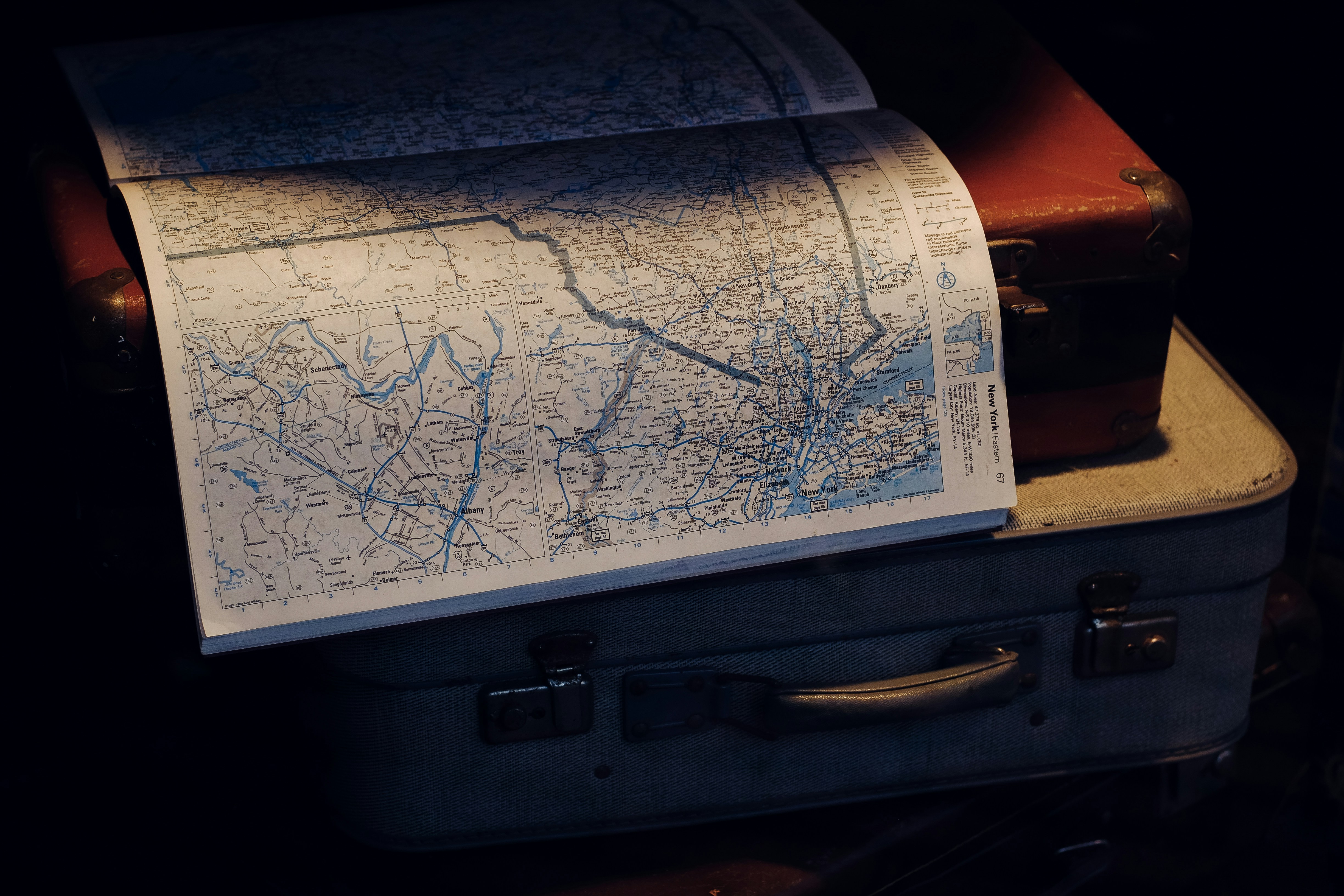 a map sitting on top of a piece of luggage, Suitcases with open map, inviting to travel