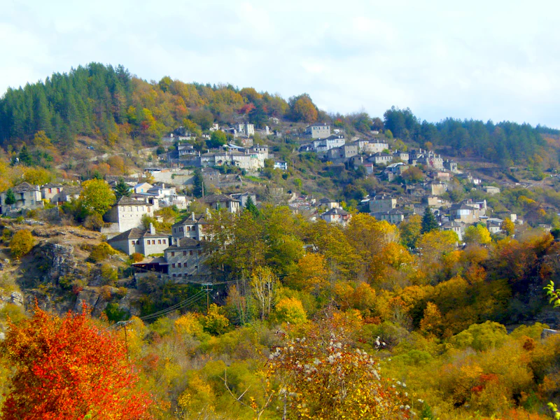 A stone village on a hillside surrounded by autumn trees