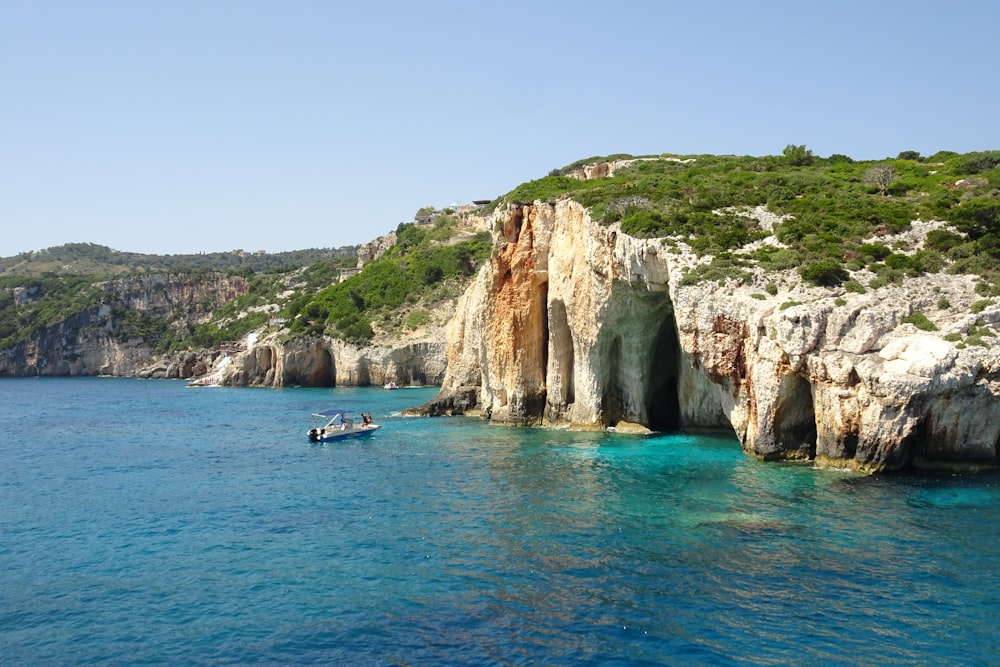 a boat in a body of water near a cliff