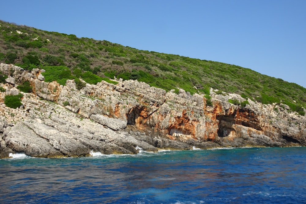 a rocky cliff on the side of a body of water