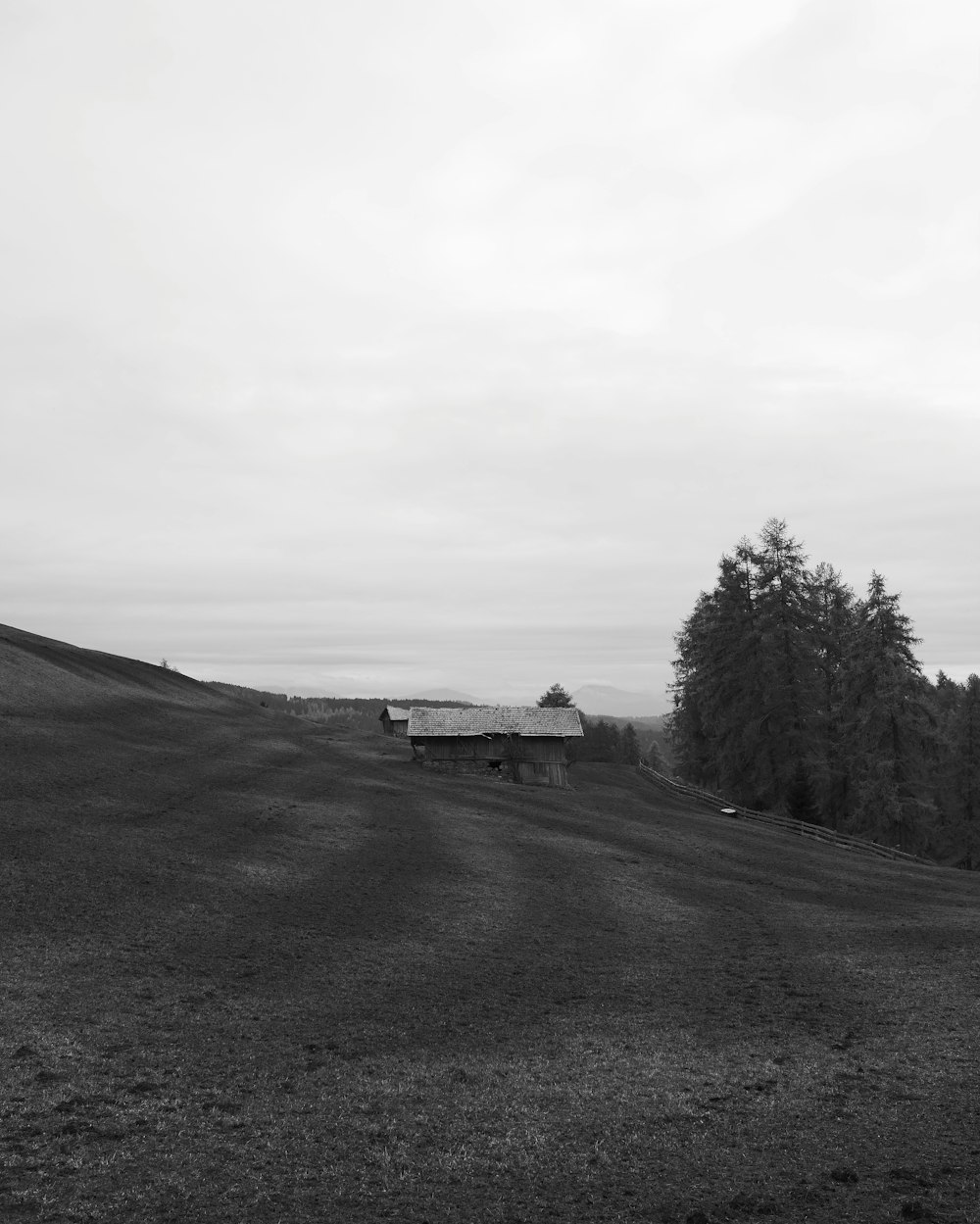 a black and white photo of a barn on a hill