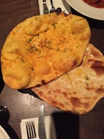 Warm, fluffy naans served alongside dipping sauces in a cozy restaurant setting.