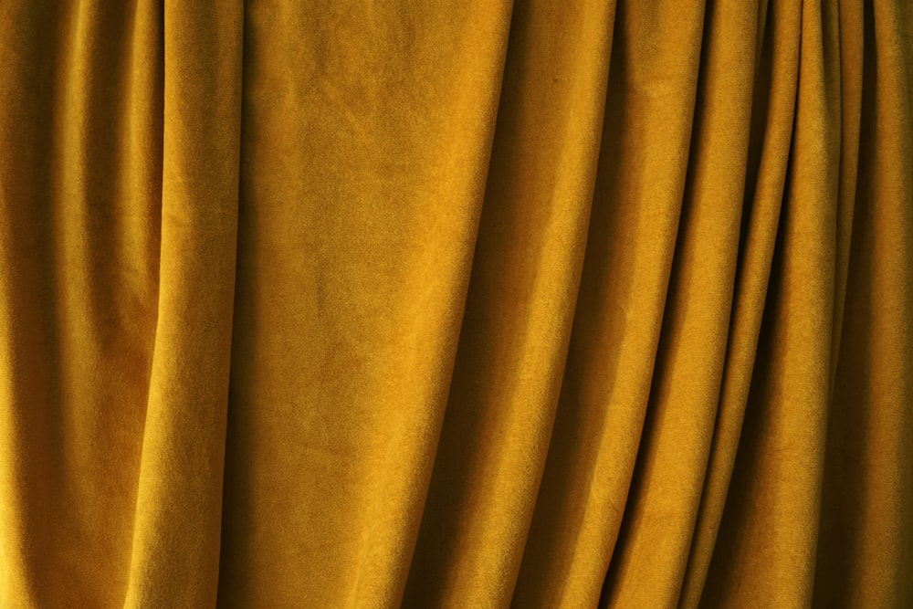 a close up of a yellow curtain with a cat sitting on top of it