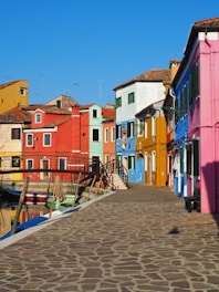 a cobblestone walkway leading to a row of colorful houses