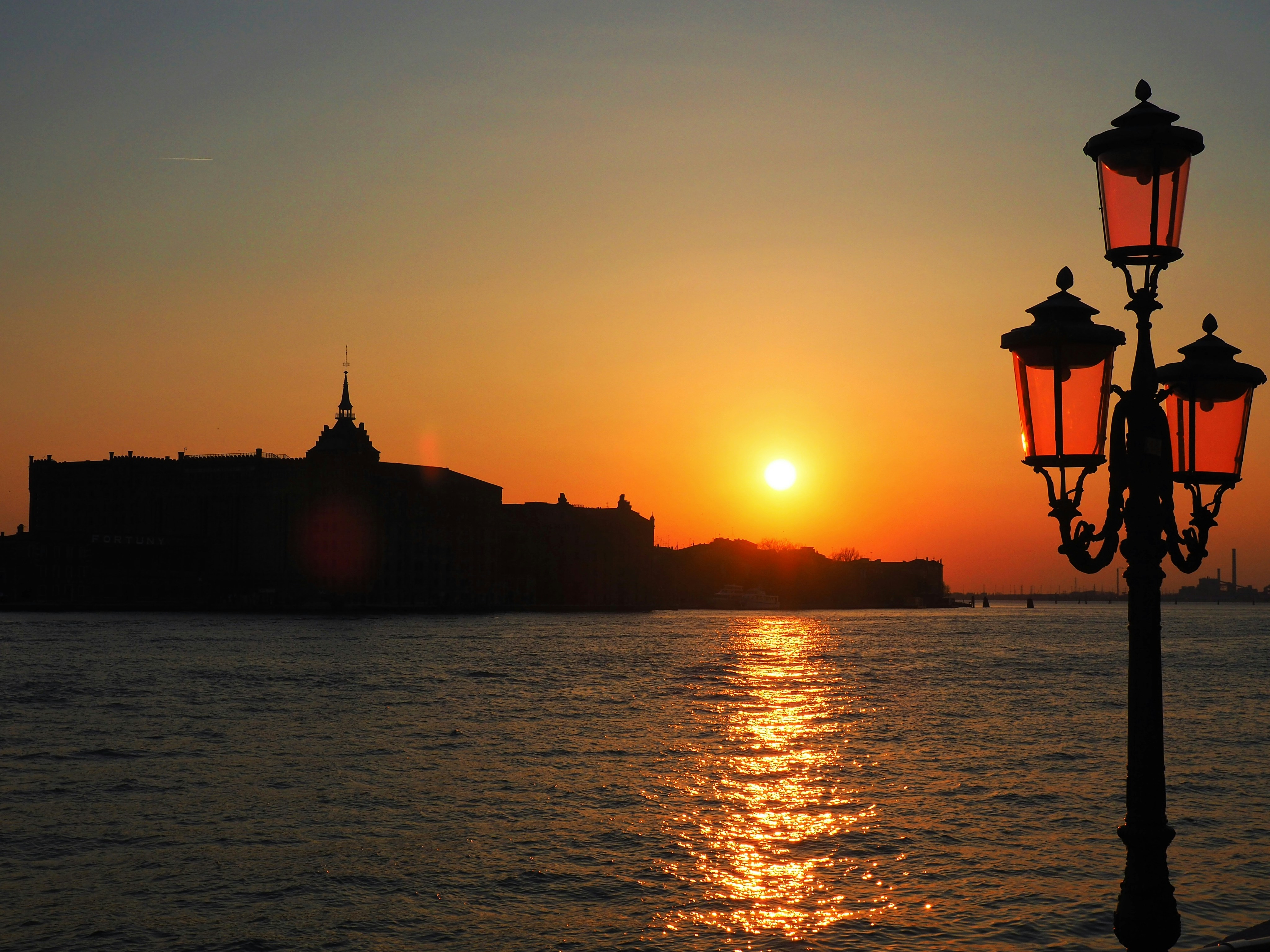 A street light sitting next to a body of water photo – Free Sunset ...