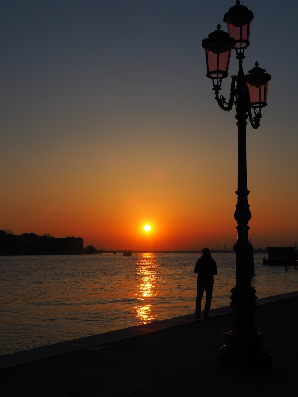 a person standing next to a lamp post near the water