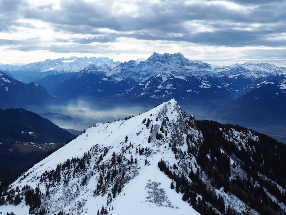 a snow covered mountain with trees and mountains in the background