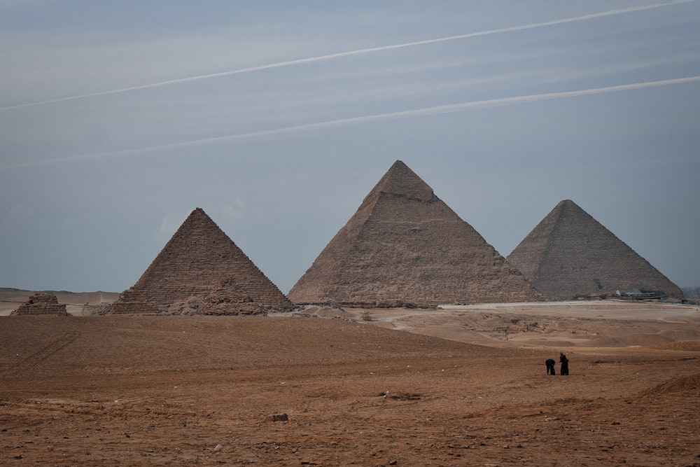 three pyramids in the desert with a sky background