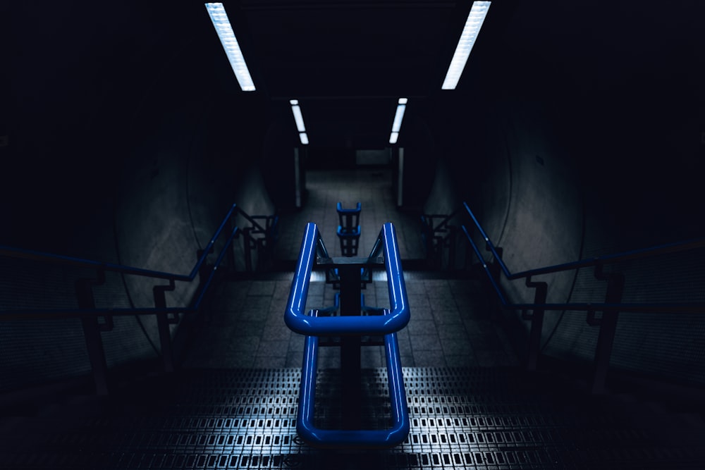 a dark hallway with blue pipes and a bench