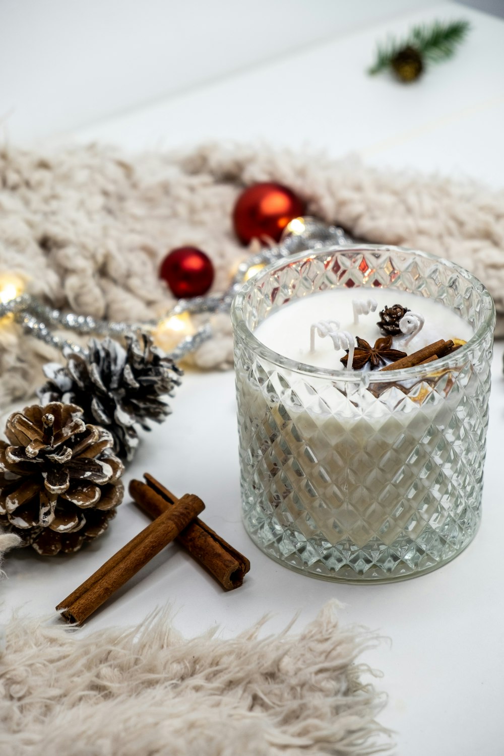 a glass candle with cinnamon sticks and a christmas decoration