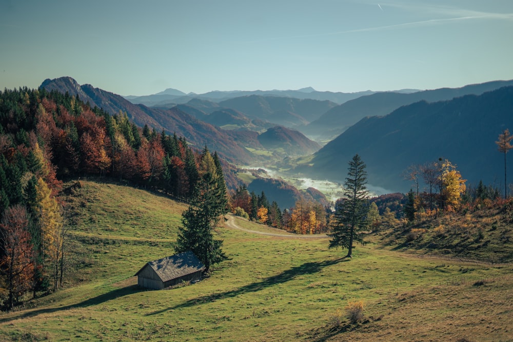 a small house on a grassy hill with mountains in the background