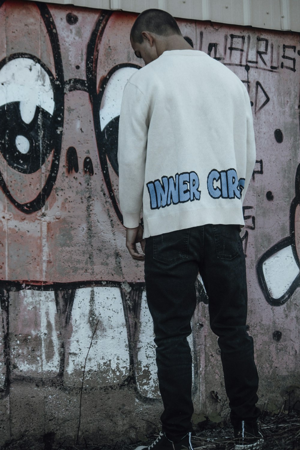 a man standing in front of a graffiti covered wall