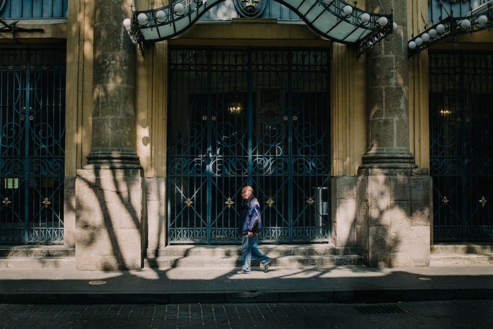 a woman walking down a street past a tall building