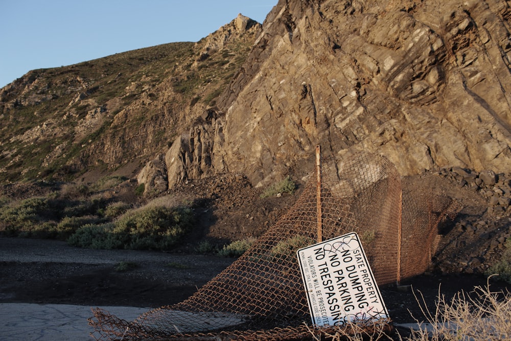 a sign that is on a fence near a mountain