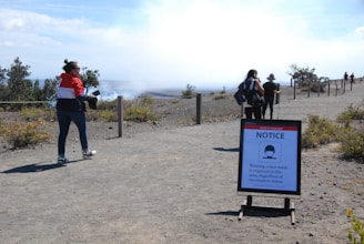 Guides leading a small group on a narrow path with Fuego volcano erupting in the distance.