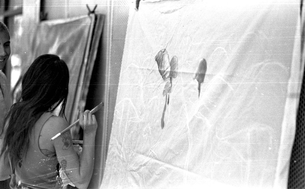 Una mujer parada junto a una pared con una pintura en ella