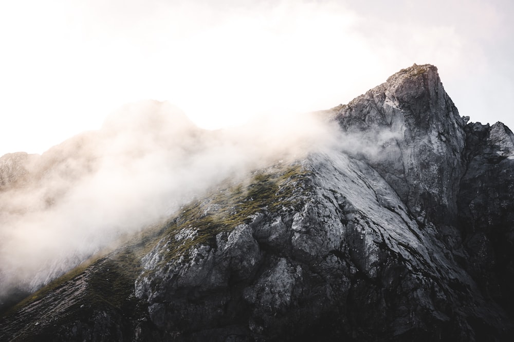 the top of a mountain with clouds coming out of it