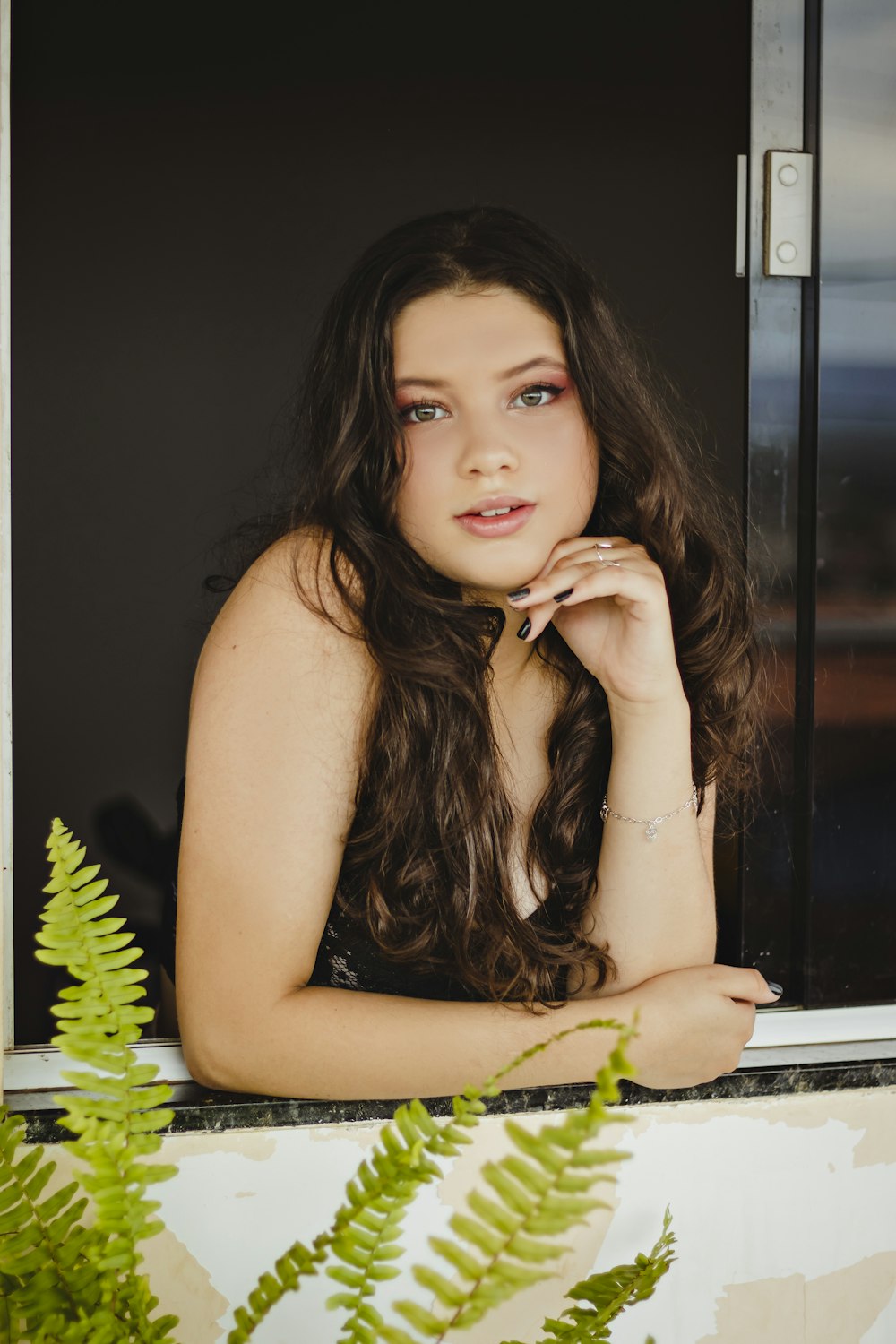 a beautiful young woman leaning on a window sill