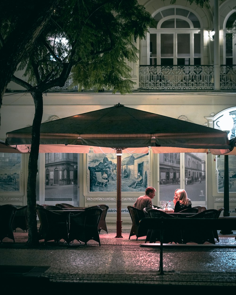 two people sitting at a table under an umbrella