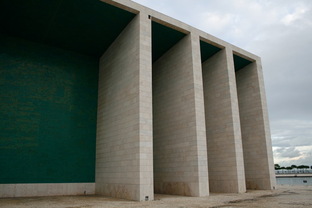 a row of concrete pillars against a green wall