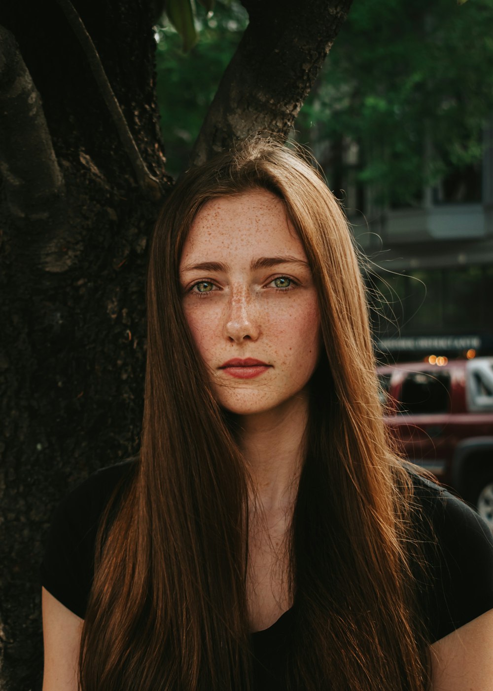 a woman with freckled hair sitting under a tree