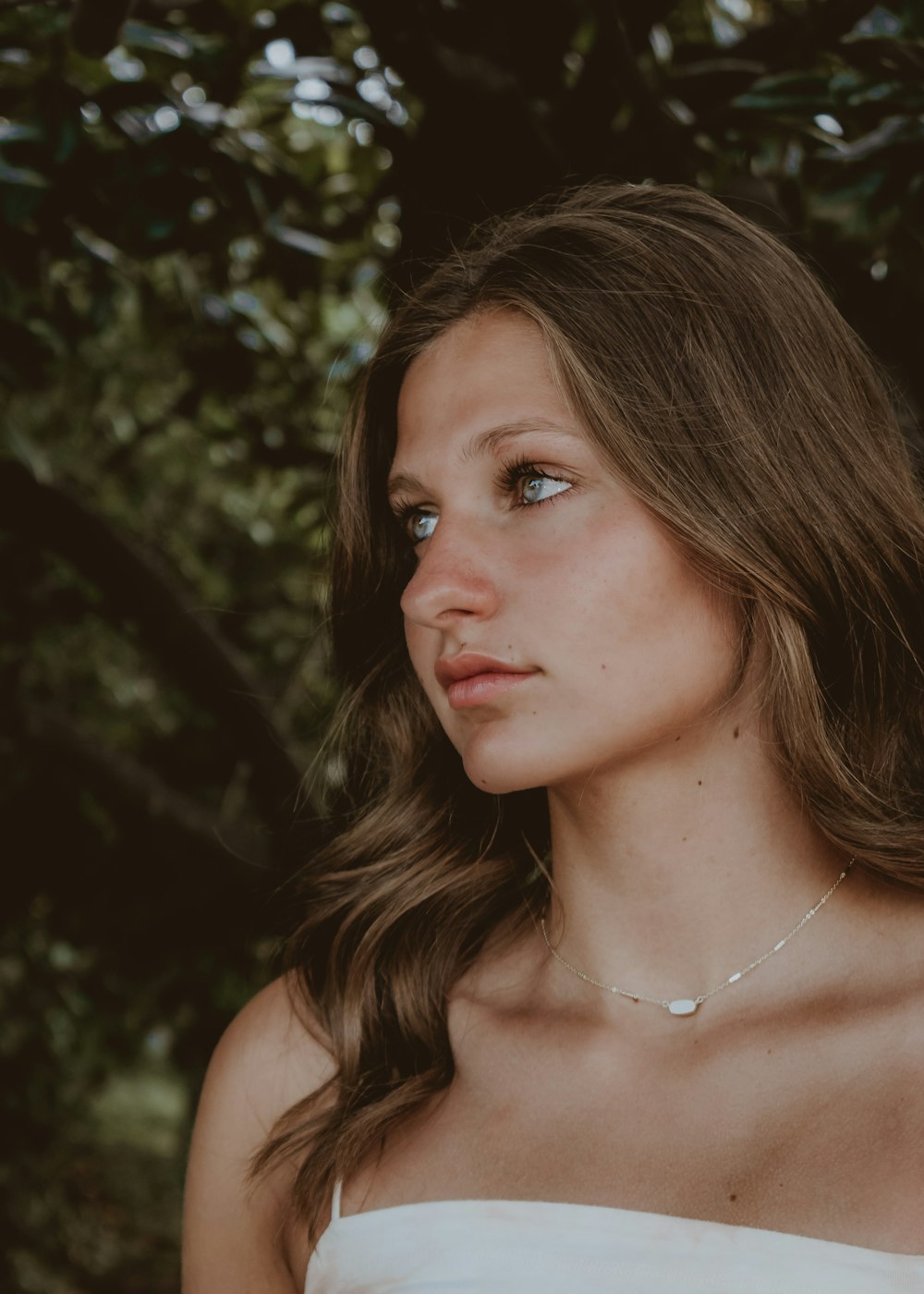 Una mujer con un vestido blanco sin tirantes posa para una foto