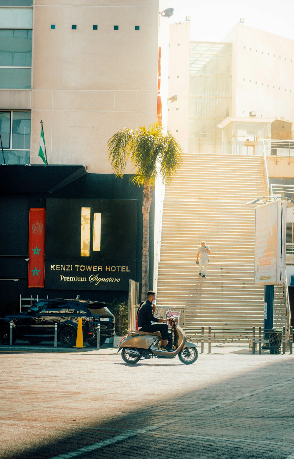 Ein Mann fährt mit dem Motorrad eine Straße neben einem hohen Gebäude entlang